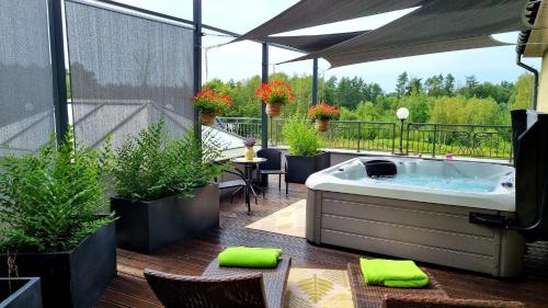 un patio con bañera de hidromasaje en un balcón con plantas en Hotel Spa Laskowo, en Jankowice