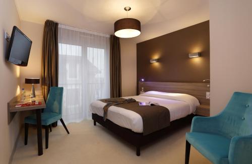 a hotel room with a bed and two chairs at The Originals City, Hôtel Les Thermes de l'Avenue, Dax in Dax