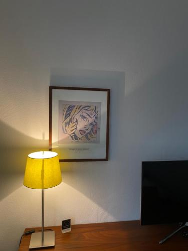 a lamp on a table with a picture on the wall at Hotel Sonderborg in Schrobenhausen