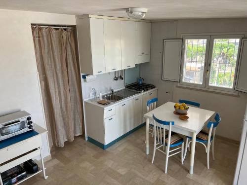 a kitchen with white cabinets and a table with chairs at Casetta di campagna da Enzo in Rilievo