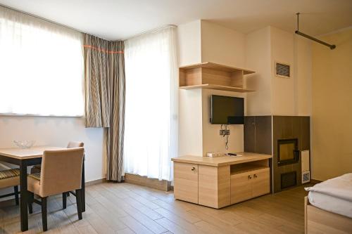 a living room with a table and a room with a bed and a television at Hotel Jirinka in Dolní Morava