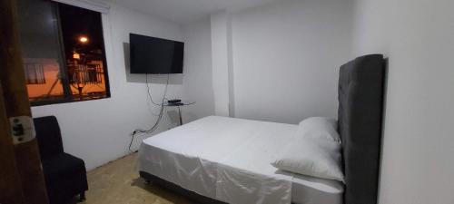 a bedroom with a white bed and a flat screen tv at Confortable apartaestudio en excelente ubicación in Pereira