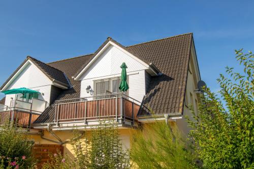 Cette maison dispose d'un balcon avec un parasol vert. dans l'établissement Maisonette-Ferienwohnung Karla, à Karlshagen