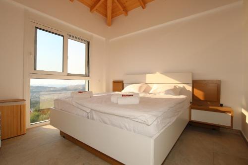 a white bedroom with a large bed and a window at Sunset Sea View Villa 8 in Afionas