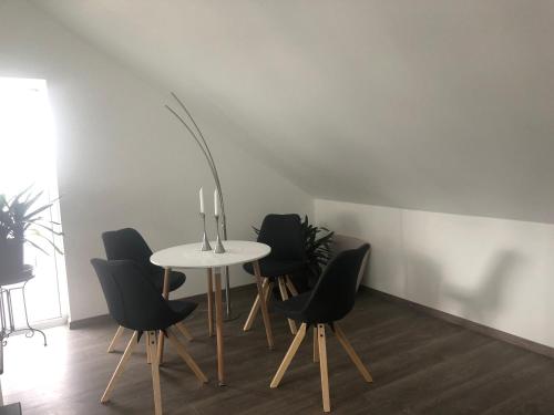 a table with four black chairs and a lamp at Zimmervermietung Krug in Eberhardzell