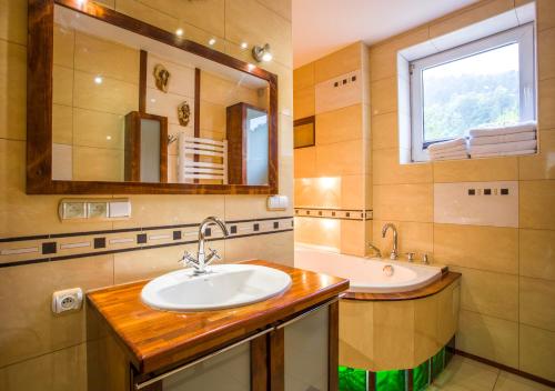 a bathroom with a sink and a tub and a mirror at Apartament Przy Parku in Muszyna