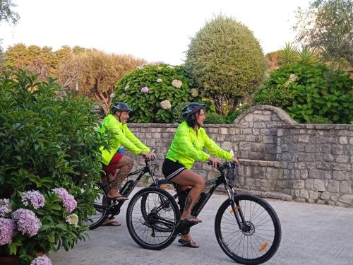 two people in yellow jackets riding bikes next to a stone wall at Casa Vacanze Nino Petrelli in Naso