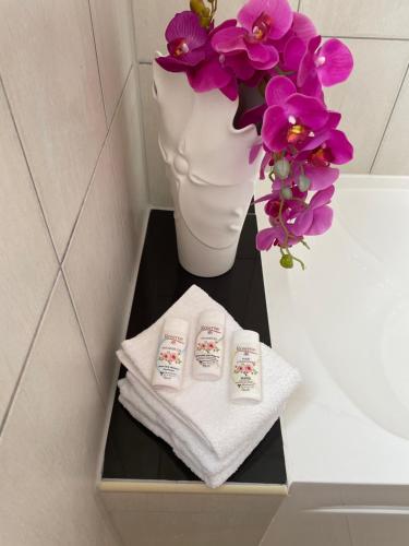 ein Regal mit zwei gefalteten Handtüchern und einer Vase mit Blumen in der Unterkunft Spring Garden Mobay Resort Luxurious Apartments in Montego Bay