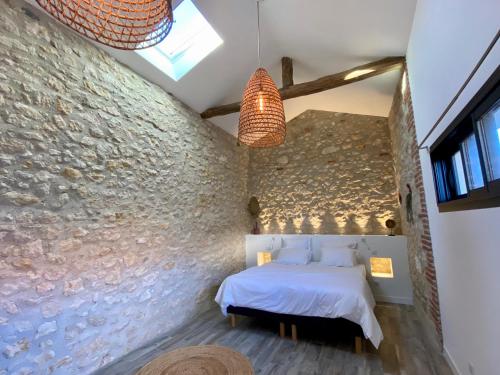 sypialnia z łóżkiem i kamienną ścianą w obiekcie Aux Rives de la Courtade w mieście Rivières