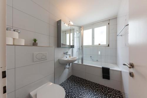a white bathroom with a sink and a toilet at Joe's Apartment am Bolgen in Davos
