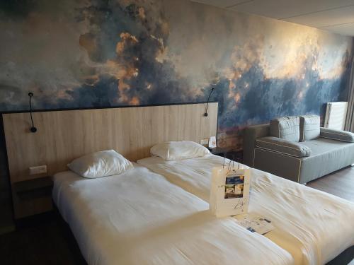 two beds in a room with a painting on the wall at Fletcher Hotel Restaurant Zeeduin in Wijk aan Zee