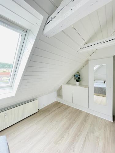 an attic bedroom with white walls and a window at aday - Charming loft studio in Aalborg