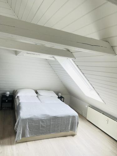 a white bedroom with a bed in a attic at aday - Charming loft studio in Aalborg