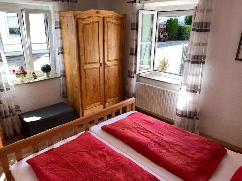 a bedroom with a bed with red sheets and two windows at FeWo HoLiDay HouSE Allgäu in Ottobeuren