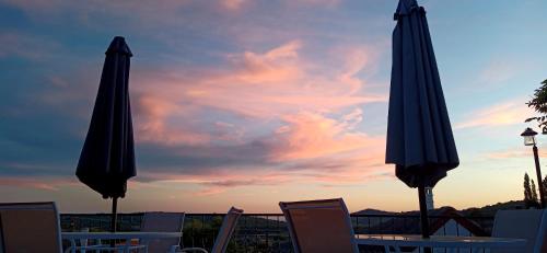 two umbrellas and chairs in front of a sunset at T.H.NY Village Inn Cottage in Tihany
