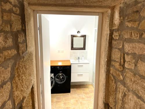 lavadero con lavadora y secadora y pared de piedra en La Duchesse - Grand Appartement Au Coeur de Dijon en Dijon
