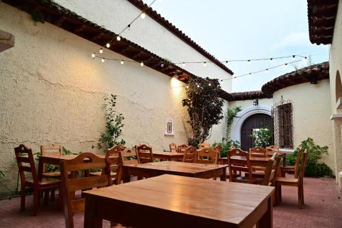 un patio con mesas de madera, sillas y luces en Ricks hostel Santa Ana, en Santa Ana