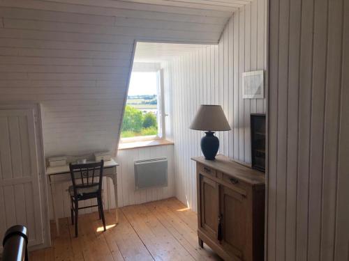 Cette chambre comprend un bureau avec une lampe et une fenêtre. dans l'établissement Magnifique longère du Cotentin, à Heugueville-sur-Sienne