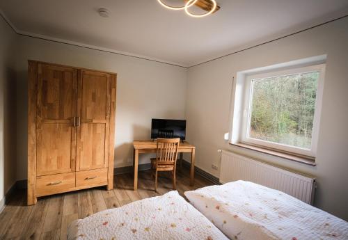 a bedroom with two beds and a desk with a window at Kleines Bahnhofshotel (Gästezimmer) in Greifenstein