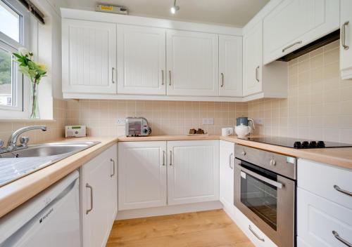 een witte keuken met witte kasten en een wastafel bij Bayview Bungalow 365 in Oxwich