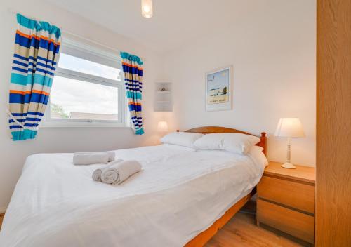 sypialnia z dużym białym łóżkiem z ręcznikami w obiekcie Bayview Bungalow 365 w mieście Oxwich