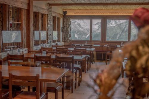 un comedor con mesas, sillas y montañas en Hotel Eggishorn, en Fiesch