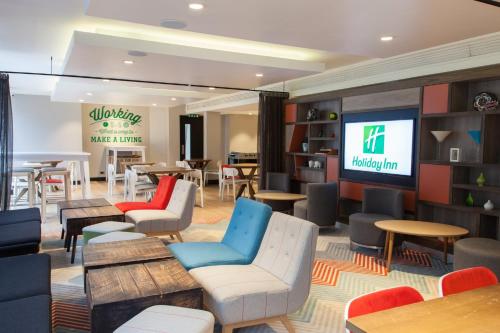 a waiting room with chairs and tables and a tv at Holiday Inn London Camden Lock by IHG in London