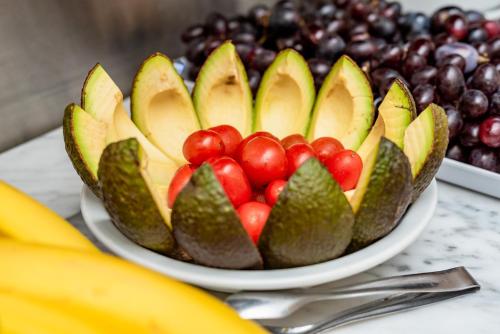 a bowl of fruit with apples and grapes on a table at Hotel Bys Palermo in Buenos Aires