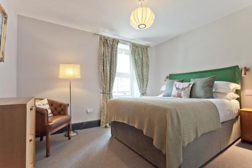 a bedroom with a bed and a chair and a window at Bumble Choo Cottage - Windermere, Lake District in Windermere