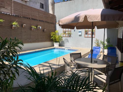 un patio con mesa, sombrilla y piscina en Pousada da Praia, en Paraty