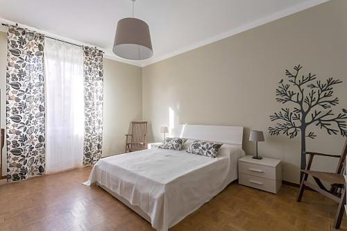 een witte slaapkamer met een bed en een boom aan de muur bij Natural chic - Close to city center and beach - parking in Desenzano del Garda