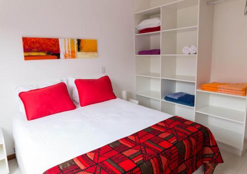 a bedroom with a bed with red pillows and shelves at Pousada Maiken in Florianópolis