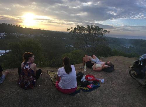 a group of people sitting on a hill watching the sunset at Rinjani Houseboon in Senaru