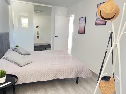 a white bedroom with a bed and a mirror at Copacabana ocean view apartament in Playa Fañabe
