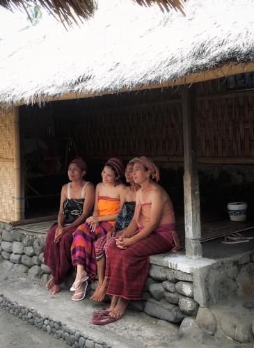 a group of people sitting outside of a hut at Rinjani Houseboon in Senaru