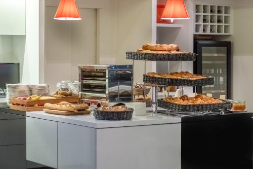 a counter with several tiers of pastries and bread at The Originals City, Hôtel Les Thermes de l'Avenue, Dax in Dax