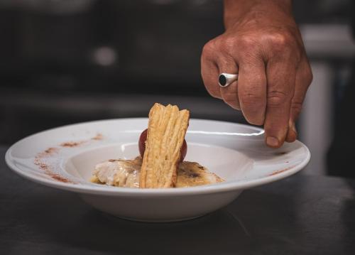 a person holding a plate with a bowl of food at The Originals City, Hôtel Les Thermes de l'Avenue, Dax in Dax