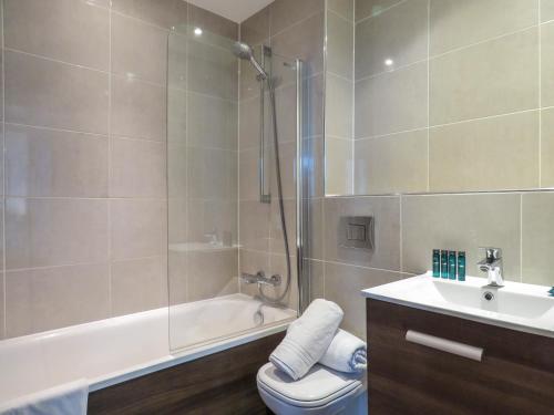 ein Bad mit einer Dusche, einem WC und einem Waschbecken in der Unterkunft Tudors eSuites Five Ways Two Bedroom Apartment in Birmingham