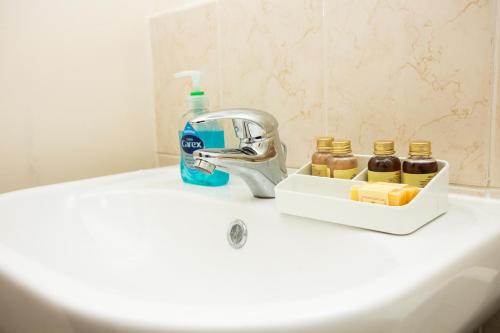 - un lavabo avec un porte-brosse à dents et une bouteille de dentifrice dans l'établissement SUMMIT Apartment - Cozy Aberdeen West End Flat Prime Location - Perfect for Short or Long stay - 1 bedroom, à Aberdeen