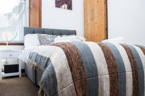 een slaapkamer met een bed met een deken erop bij SUMMIT Apartment - Cozy Aberdeen West End Flat Prime Location - Perfect for Short or Long stay - 1 bedroom in Aberdeen
