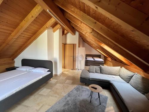 een slaapkamer met een bed en een bank op zolder bij Weidehaus Pförring in Pförring