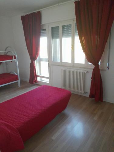 a bedroom with a red bed and two windows at APPARTAMENTO DAI DO FRADEI in Fossalta di Portogruaro
