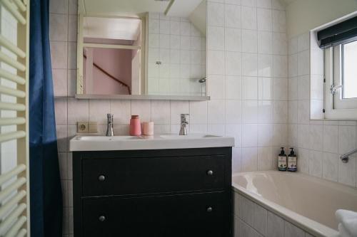 a bathroom with a sink and a bath tub at Cottage Hazenhorst - paradijs aan het bos in IJhorst