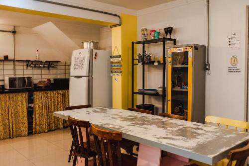 y cocina con mesa, sillas y nevera. en Lamparina Hostel en São Paulo