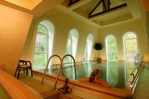 a woman laying in a swimming pool in a house at Humboldt Park Hotel & Spa in Karlovy Vary