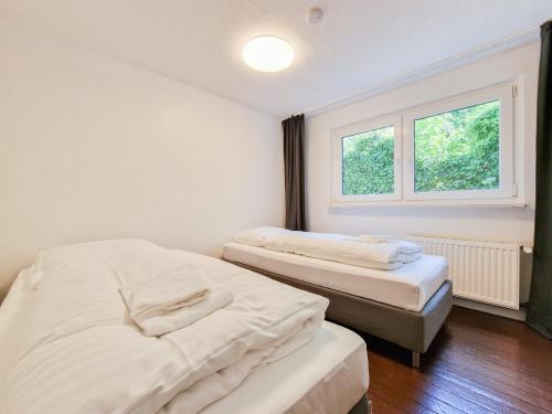 two beds in a room with a window at Tolstov Apartments - 3 Room Apartments with Garden - 20 Min Messe DUS & Airport DUS in Meerbusch