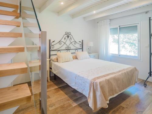a white bedroom with a bed and a staircase at Cubo's Finca La Fuente del Pedregal Casa 2 in Coín