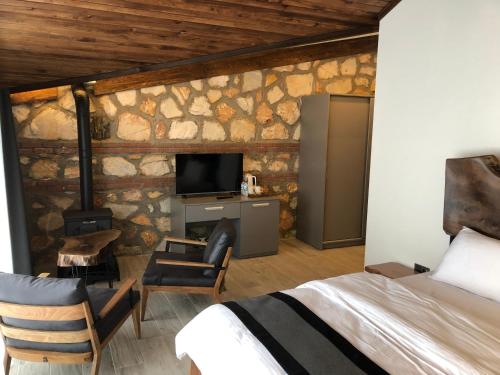 a bedroom with a bed and a tv in a stone wall at Masklavi in Kestel