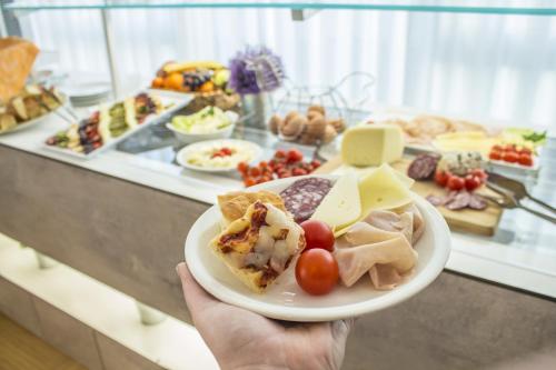 a person holding a plate of food on a buffet at Hotel Sandra in Rimini