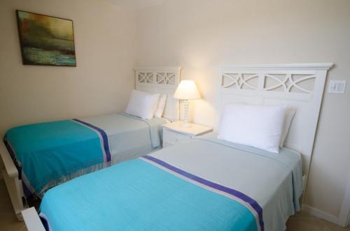 two twin beds in a hotel room with a lamp at Lantana Resort Barbados by Island Villas in Saint James